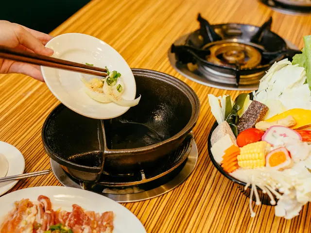 On the left corner of the picture, we see a person holding plate in their hands and we see a table...